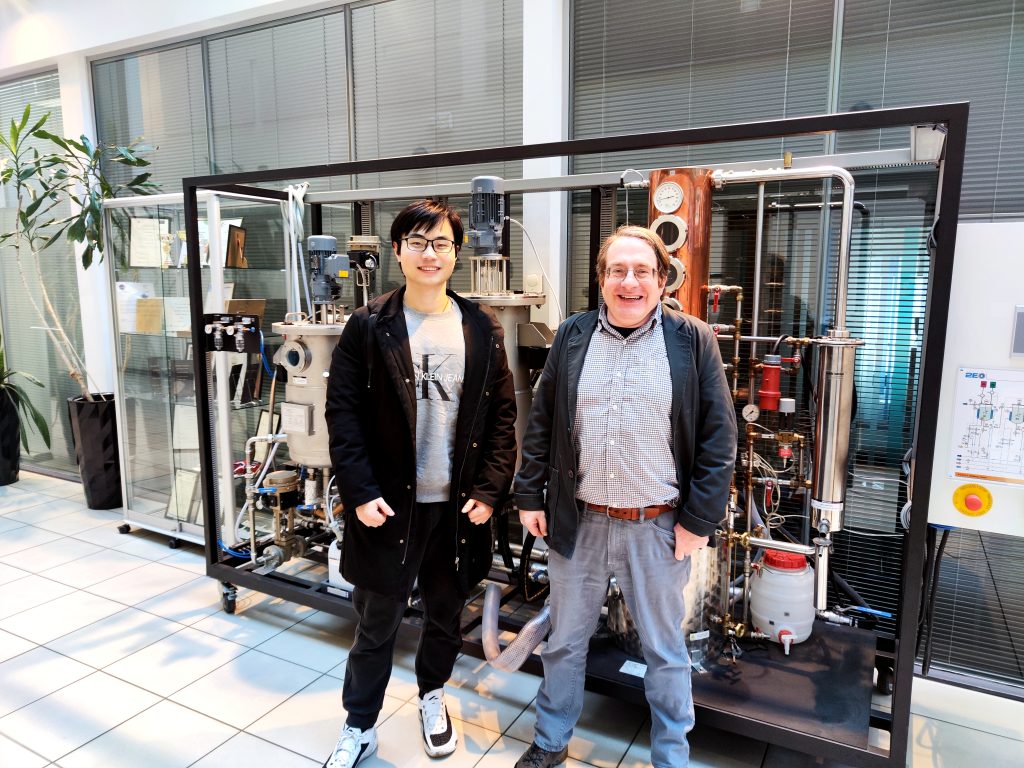 Photograph of Researcher Yuzhou Tang and Co-Investigator Tim Cockerill, posing in front of a reactor